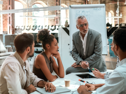 Four professionals engaged in a discussion in a meeting.